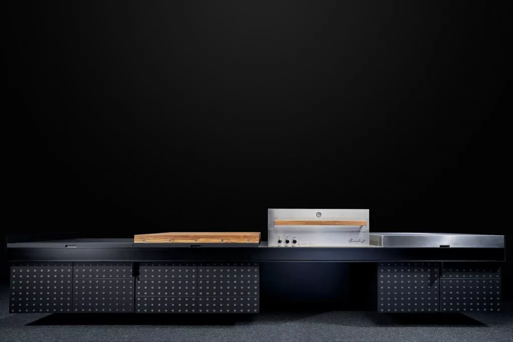 Moderne Outdoor-Küche mit dunklem Design, Nietenmusterschränken und Edelstahl-Grill.