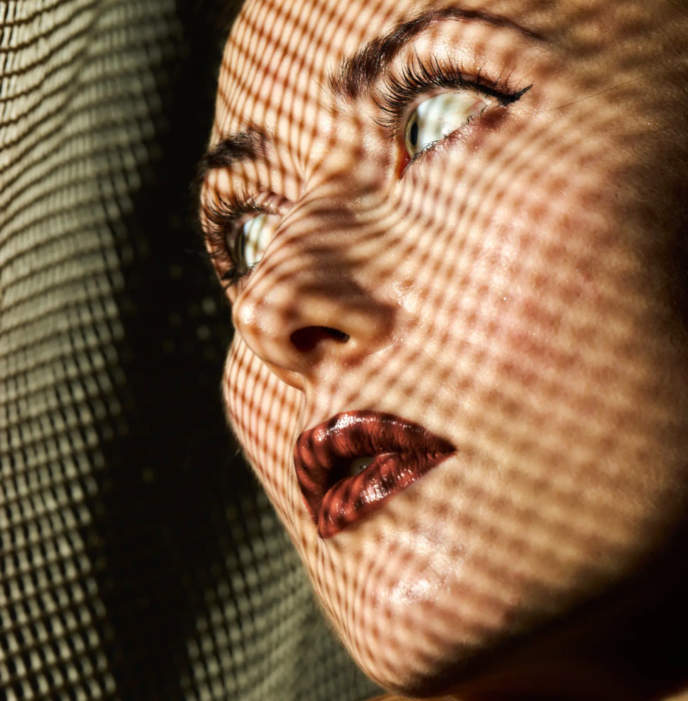 Nahaufnahme eines Gesichts mit Gittermuster-Schatten, die die Gesichtszüge betonen.