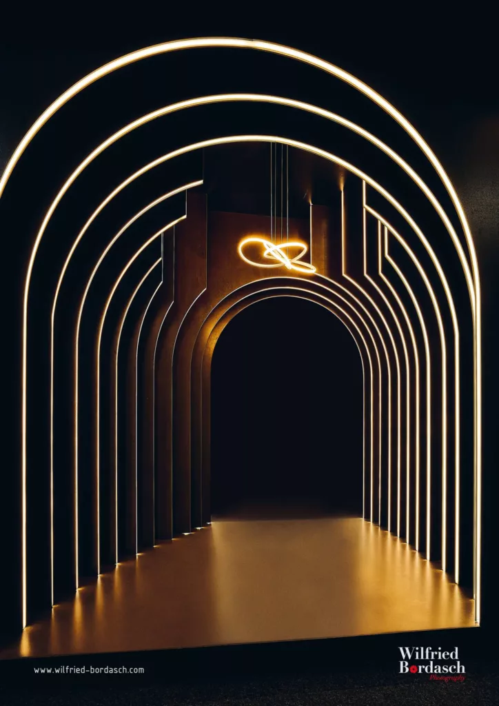 Beleuchteter Tunnel mit geschwungenen Linien und leuchtendem Element an der Decke.