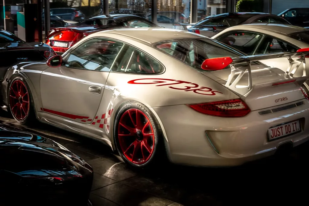 Weißer Sportwagen GT3 RS mit roten Akzenten und Spoiler in Ausstellungshalle.