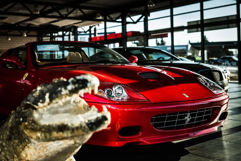 Rotes Sportauto in Ausstellungsraum mit Krokodilkopf im Vordergrund.