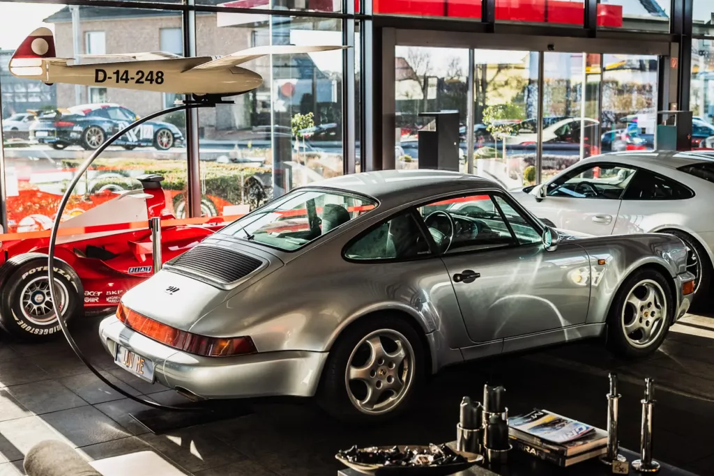 Silberner Sportwagen im Ausstellungsraum neben rotem Formelauto, weißem Sportwagen, Modellflugzeug