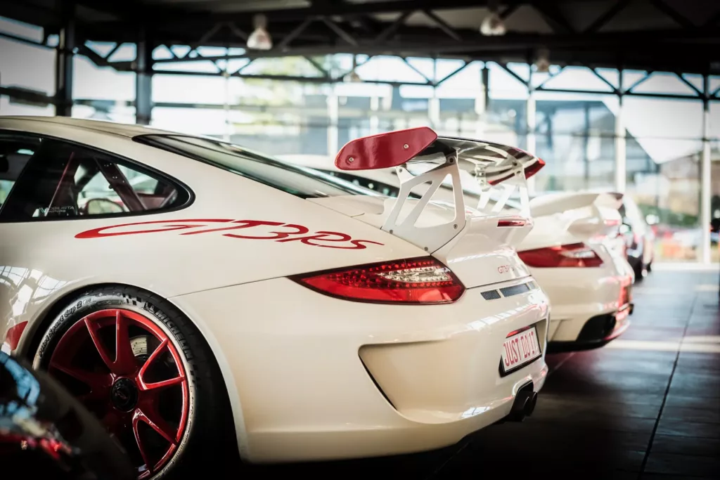 Weißer Sportwagen GT3 RS mit rotem Heckspoiler und Felgen in einer lichtdurchfluteten Halle