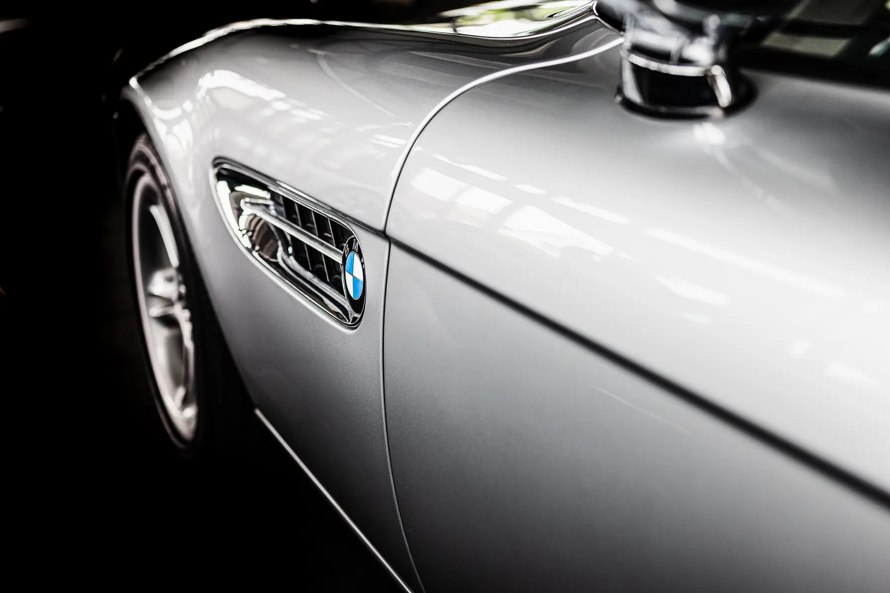 Silbernes Auto mit BMW-Emblem und seitlichem Lüftungsgitter, Nahaufnahme.