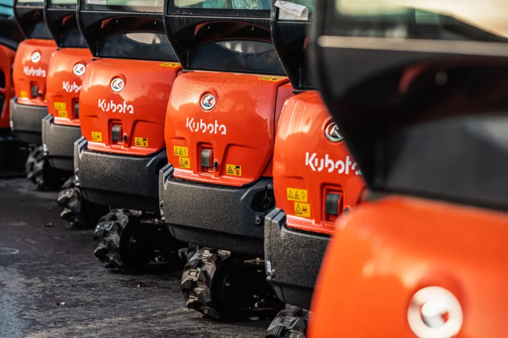 Reihe orangefarbener Kubota-Baumaschinen mit Logos und Sicherheitsaufklebern aufgestellt.