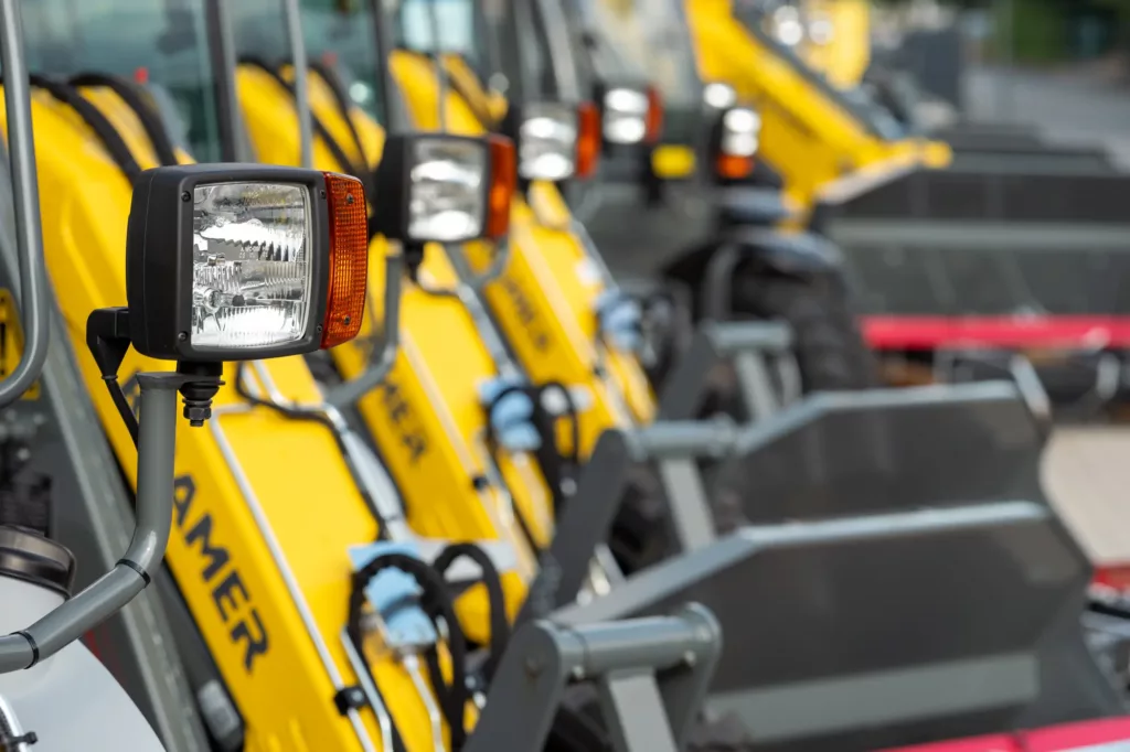 Reihe gelber Baumaschinen mit Scheinwerfern, einzelner Scheinwerfer im Vordergrund.