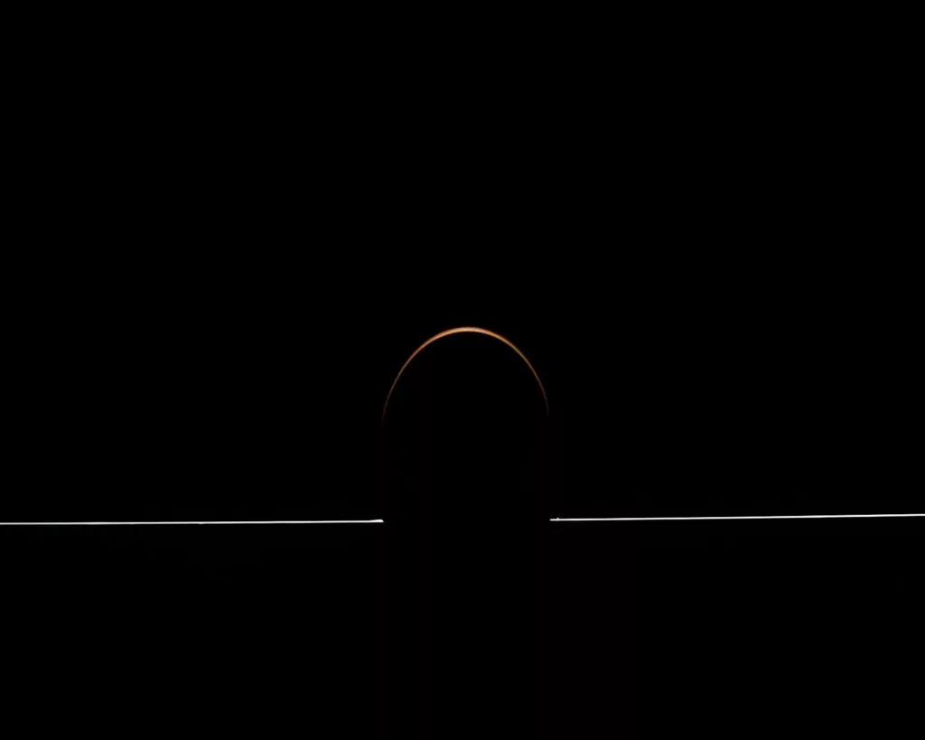 Schwarze Fläche mit schmalem leuchtenden Halbkreis und horizontaler Linie.