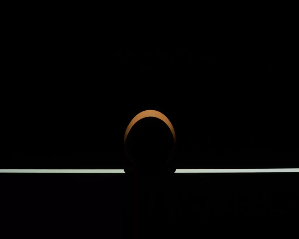 Kugelförmiges Objekt auf Linie vor dunklem Hintergrund, von oben beleuchtet.